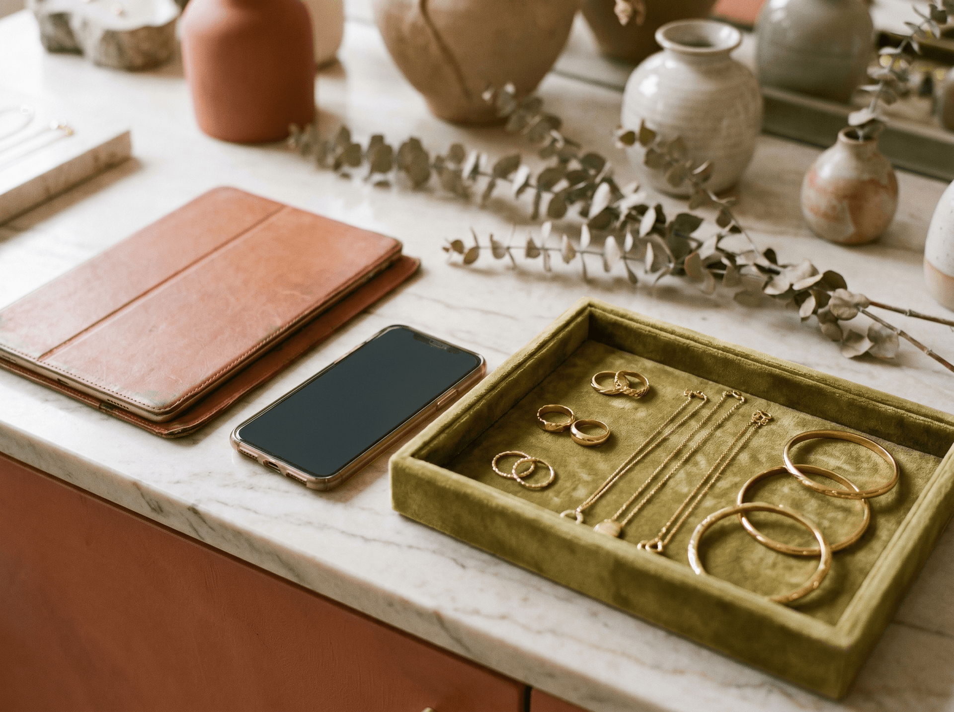 A tablet and smartphone beside a velvet tray of gold jewelry on a boutique counter
