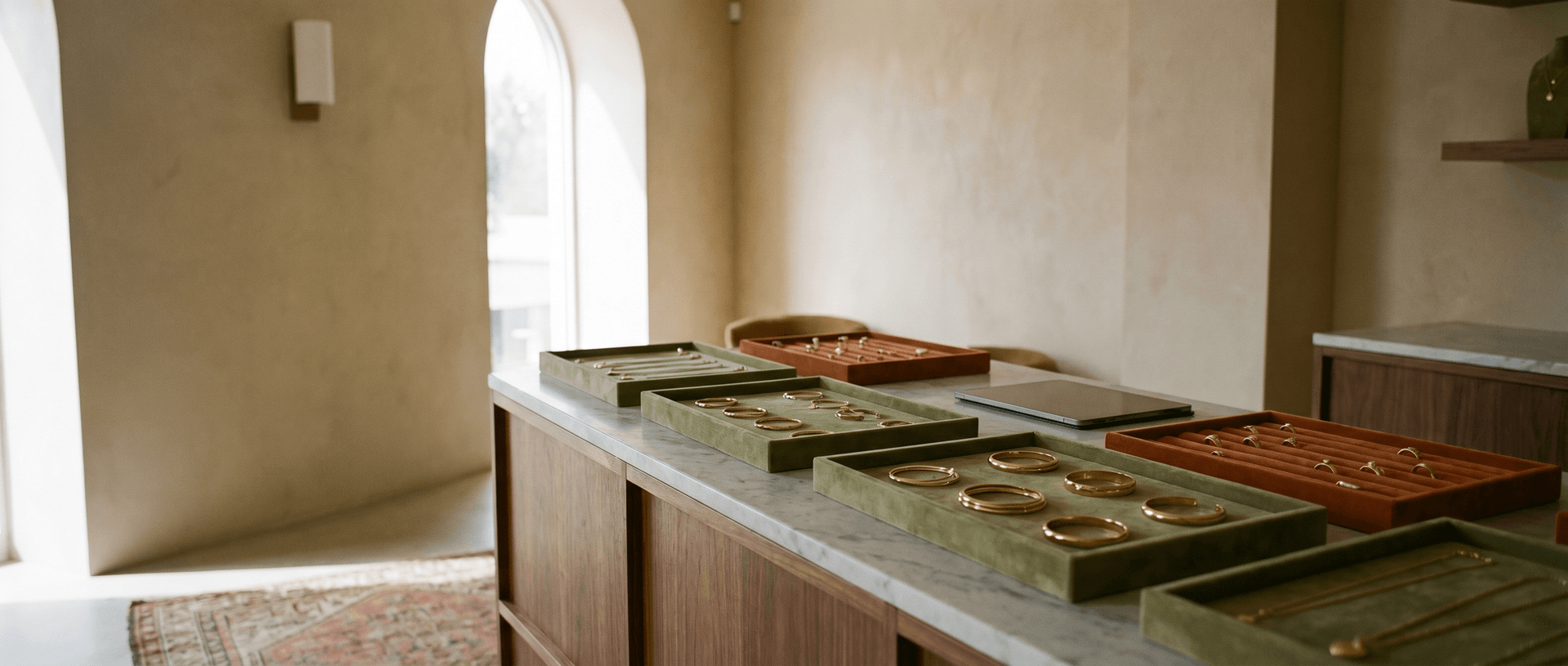 An elegant jewelry boutique counter with velvet trays of gold jewelry in warm morning light