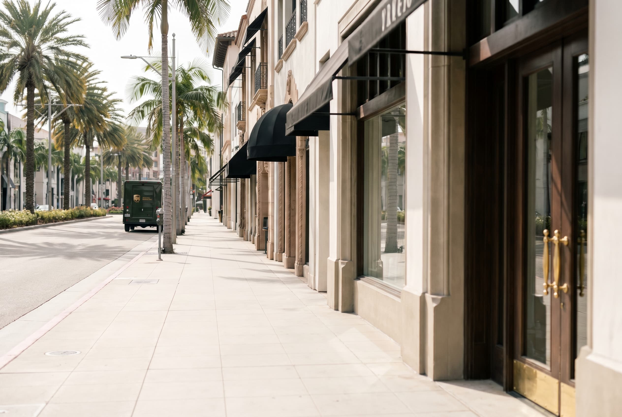 Rodeo Drive in Beverly Hills with palm trees, luxury boutique facades, black canopy awnings, early morning light