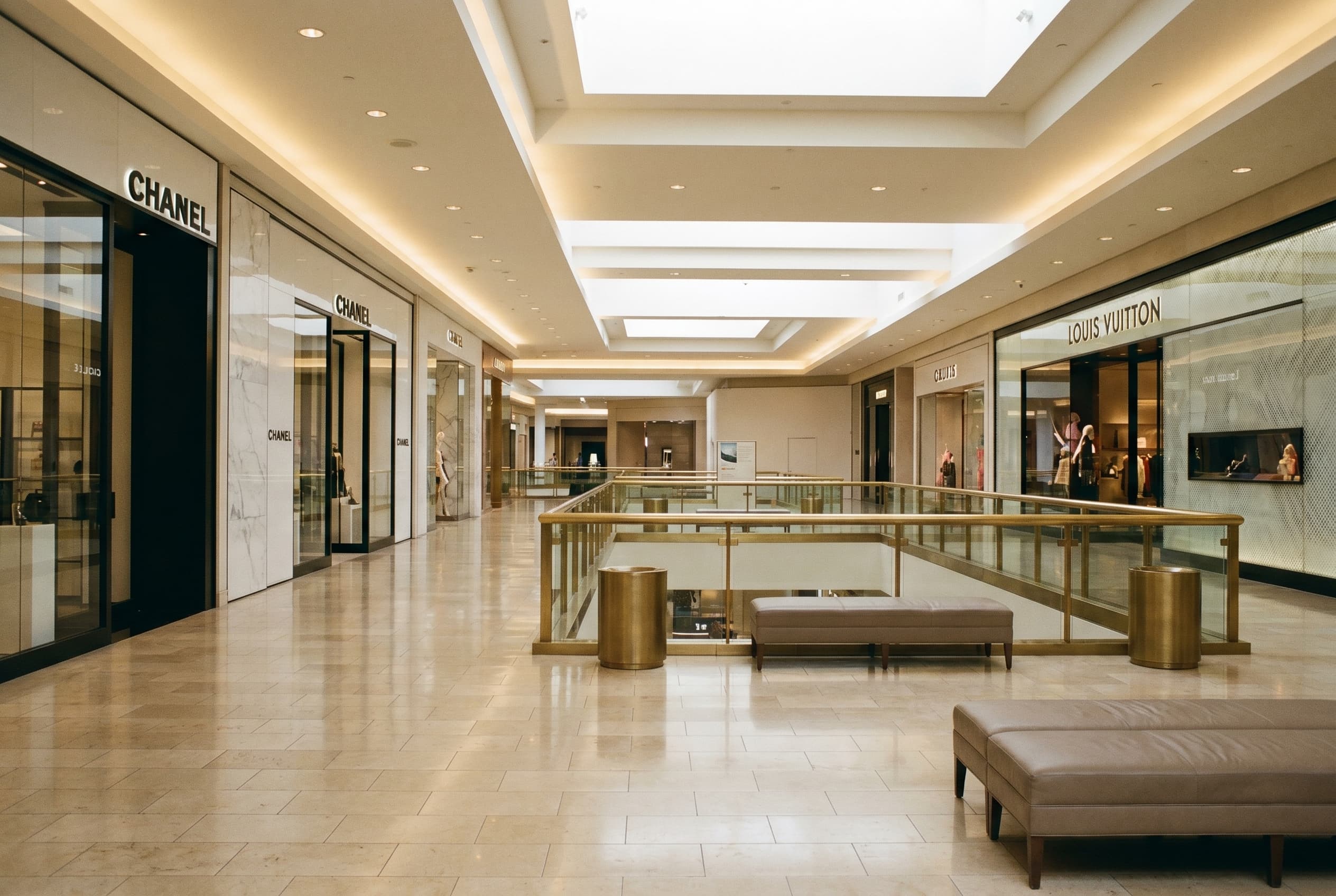 Interior of South Coast Plaza in Costa Mesa, luxury mall with travertine floors, brass railings, warm natural light