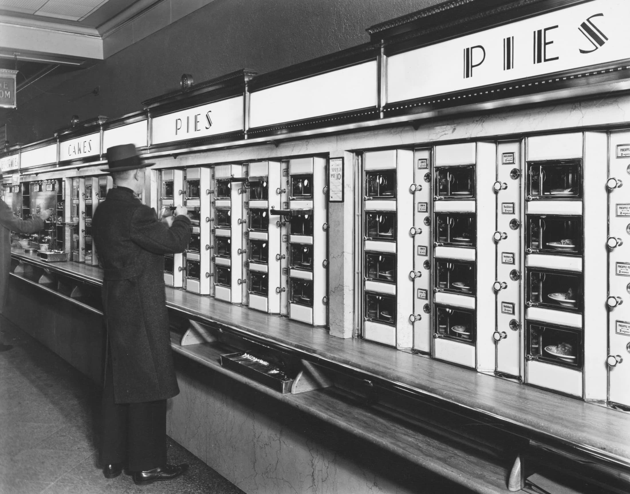 Black-and-white photograph of a customer using a row of vending machines
